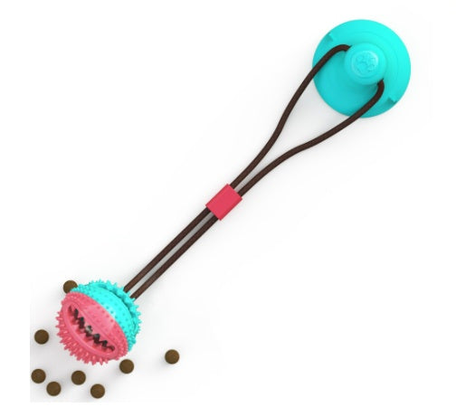 Interactive suction cup dog toy attached to a wall, with a dog pulling on it. The toy is made of silicone and features a ball with openings for teeth cleaning and a space to dispense treats.