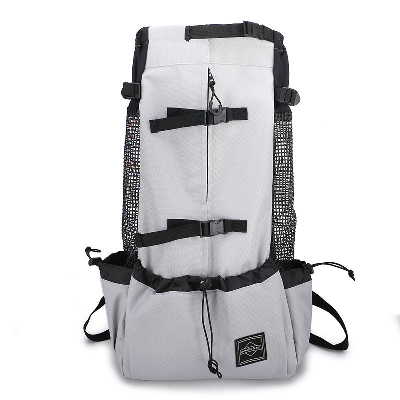 A small dog in a gray pet carrier backpack being worn by a person with adjustable shoulder straps.